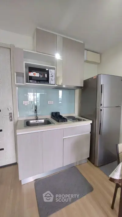 Modern compact kitchen with sleek cabinetry and stainless steel appliances in a stylish apartment.