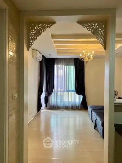 Elegant living room with chandelier and large window, featuring stylish ceiling design and cozy seating area.