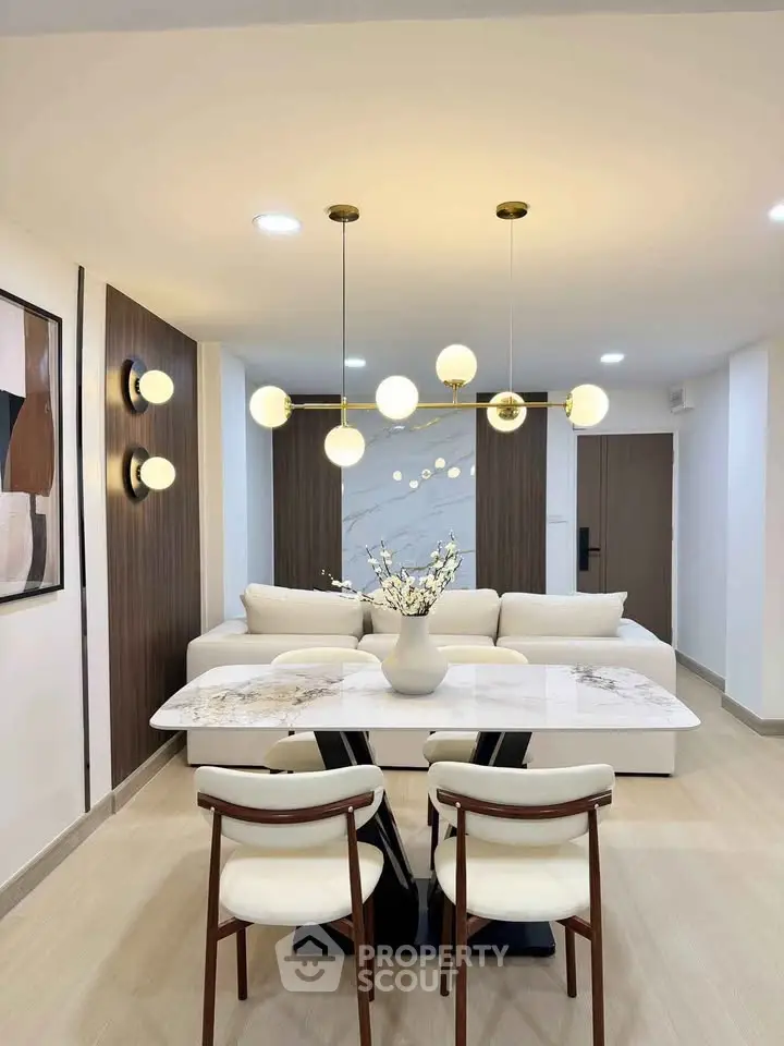 Modern living room with elegant dining area and stylish lighting fixtures.