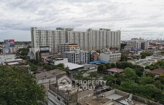 Panoramic view of urban residential buildings with lush greenery and cloudy sky.