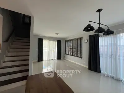 Spacious modern living room with large windows and elegant staircase
