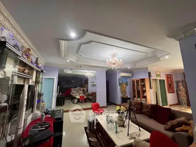 Luxurious living room with elegant ceiling design and chandelier, featuring plush seating and modern decor.