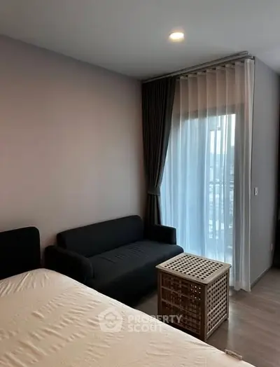 Cozy bedroom with modern decor and natural light from large window.