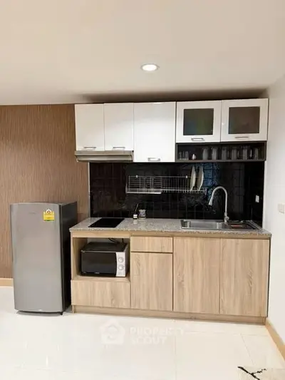Modern kitchen with sleek cabinetry, compact fridge, and built-in appliances in a stylish apartment.