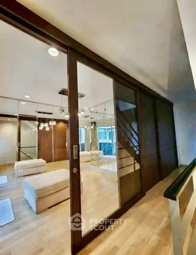 Modern interior with mirrored walls and sleek wooden sliding doors in a stylish living space.