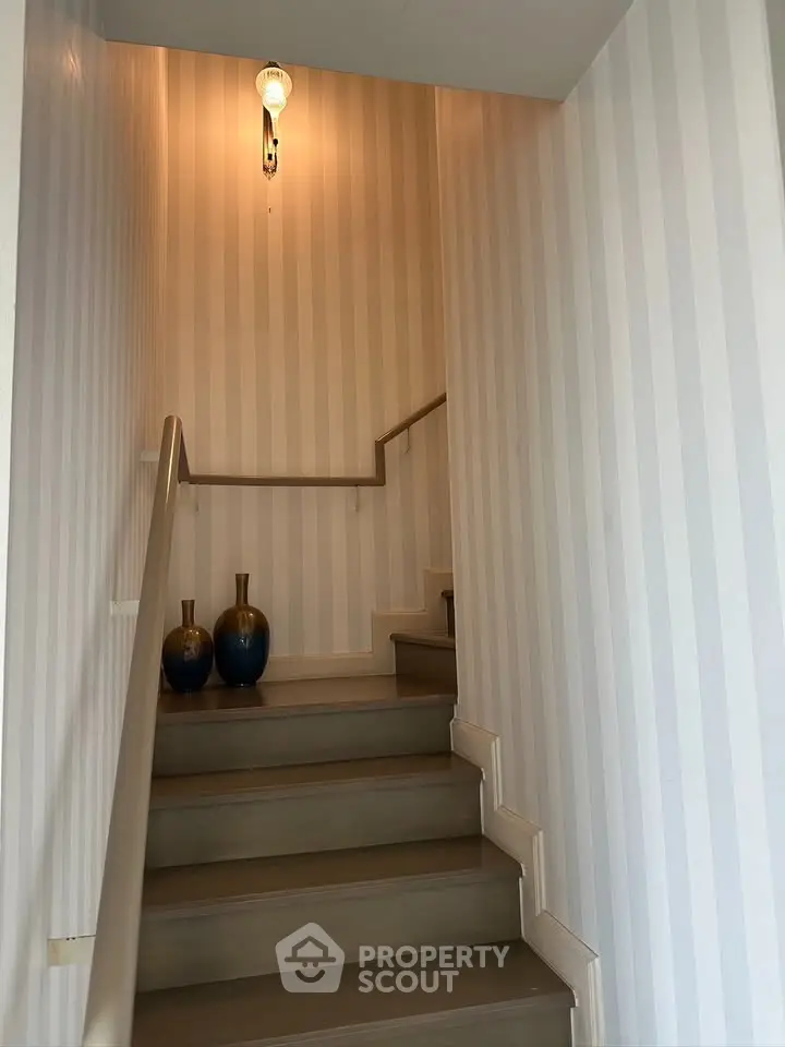 Elegant staircase with striped wallpaper and decorative vases, perfect for modern homes.