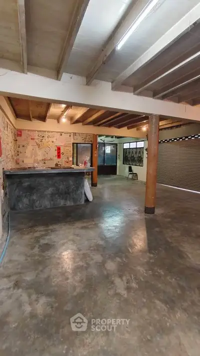 Spacious industrial-style interior with concrete floors and exposed beams, ideal for creative workspace or studio.