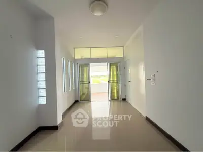 Spacious modern hallway with glossy floors and glass doors leading to a balcony with a view.