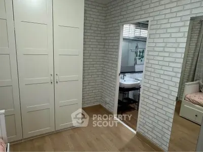 Charming bedroom with white brick walls and mirrored closet reflecting a cozy ambiance.