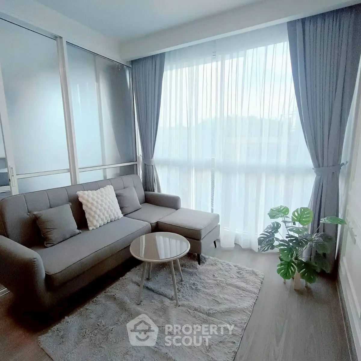 Bright and cozy living room with modern gray sofa and large window.