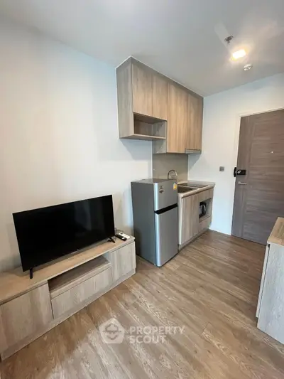 Modern compact living space with sleek kitchen and TV setup