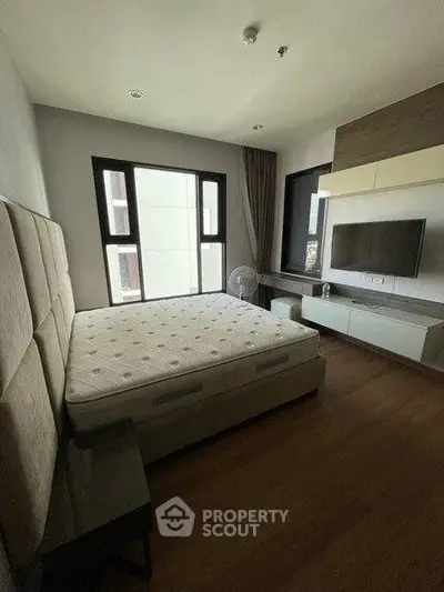 Modern bedroom with large windows and mounted TV in a stylish apartment.