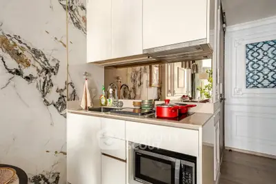 Modern kitchen with marble accents and built-in microwave, featuring sleek cabinetry and stylish decor.