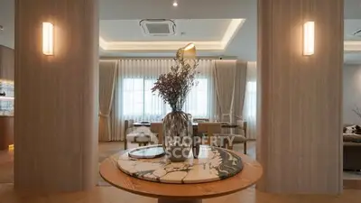 Elegant living room with modern decor and natural lighting, featuring a stylish round table centerpiece.