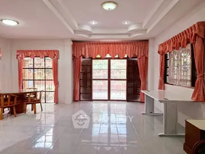 Spacious living room with large windows and elegant curtains, perfect for natural light.