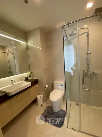 Modern bathroom with glass shower and sleek vanity in luxury apartment.