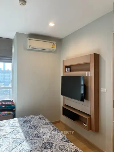 Modern bedroom with wall-mounted TV and air conditioning, featuring stylish decor and city view.