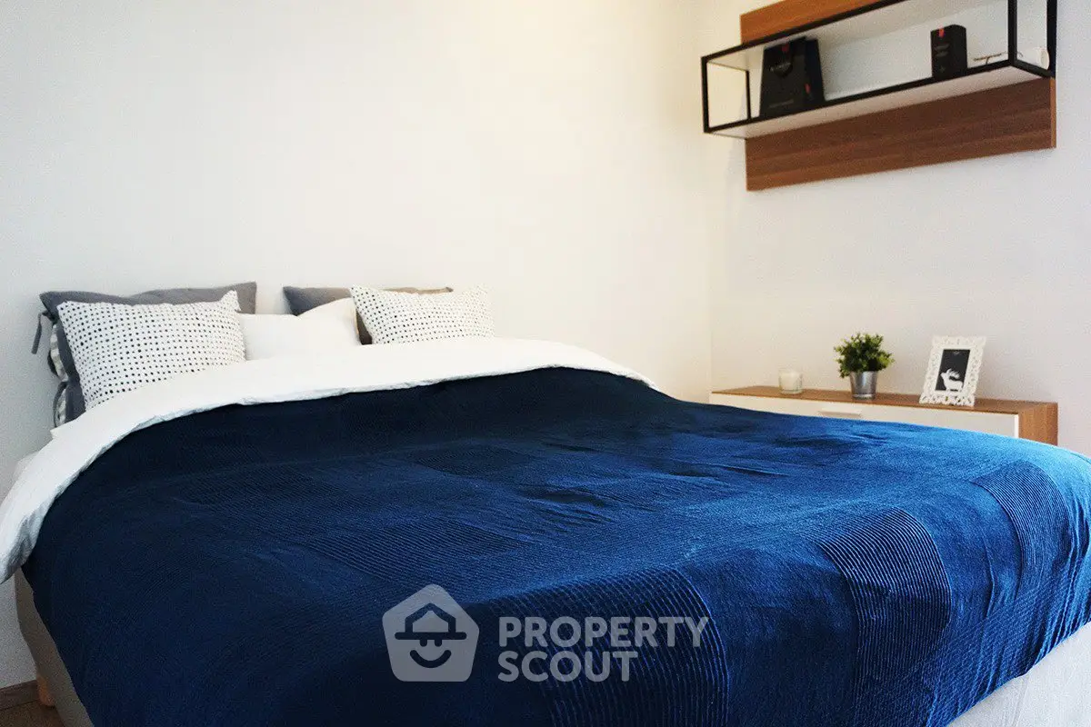 Cozy bedroom with modern decor and plush blue bedding, perfect for relaxation and comfort.