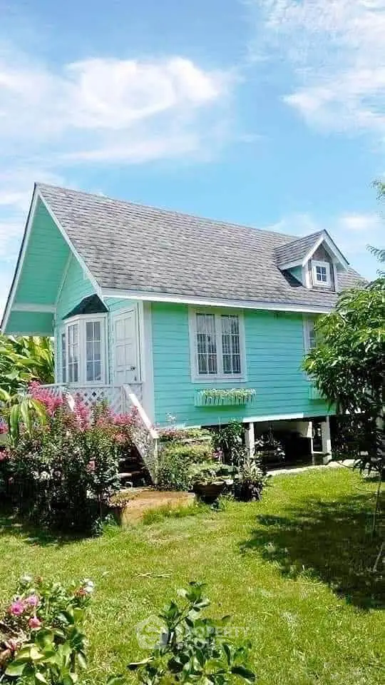 Charming turquoise cottage with lush garden and picturesque surroundings.