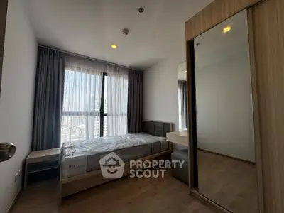 Modern bedroom with large window and wooden furniture, offering a cozy and bright living space.