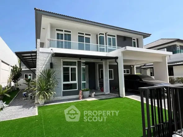 Modern two-story house with manicured lawn and sleek carport in a suburban neighborhood.