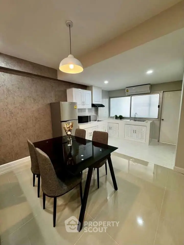 Modern kitchen with dining area featuring sleek black table and stylish chairs, perfect for contemporary living.