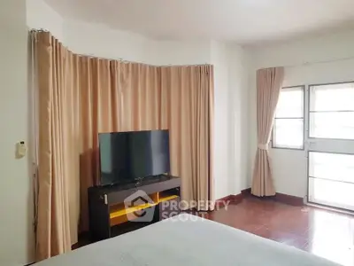 Spacious bedroom with large window and modern TV setup