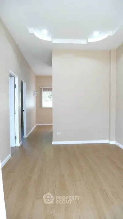 Spacious empty room with wooden flooring and modern ceiling lights