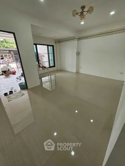 Spacious unfurnished living room with glossy tiled floors and modern lighting.