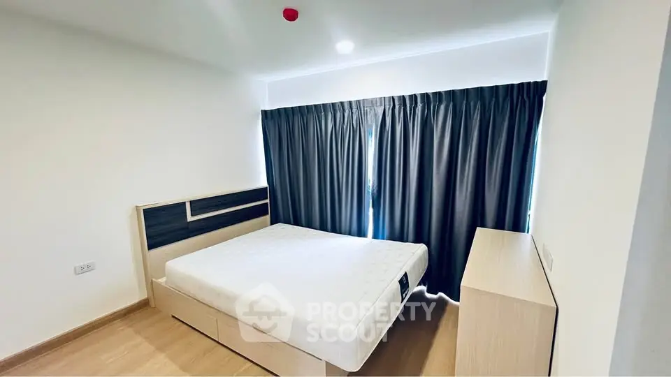 Modern bedroom with minimalist design and large window with blackout curtains.