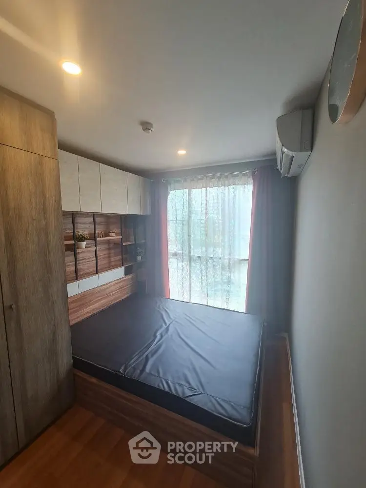 Cozy bedroom with modern wooden furnishings and large window for natural light.
