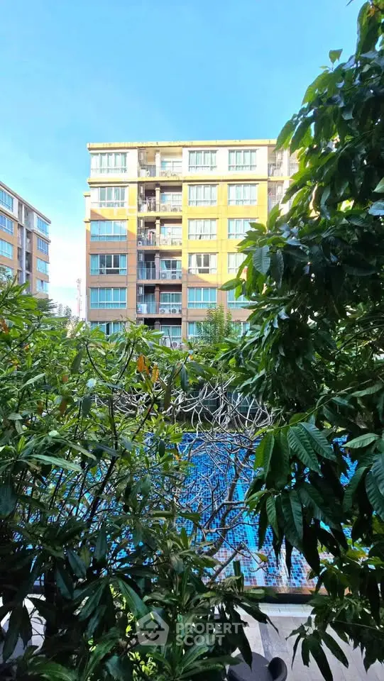 Stunning view of modern apartment building with lush greenery and inviting pool area.