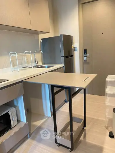 Modern compact kitchen with sleek appliances and movable island in a stylish apartment.