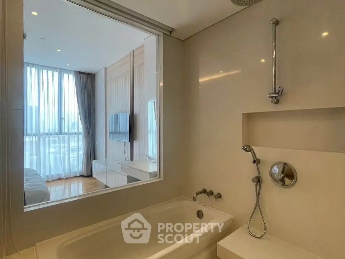 Modern bathroom with bathtub and view into stylish bedroom