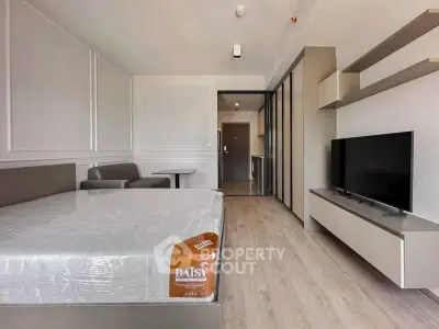 Modern studio apartment with sleek design, featuring a cozy bed, stylish TV unit, and elegant flooring.