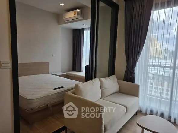 Modern apartment interior with cozy living area and bedroom, featuring large windows and natural light.