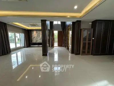 Spacious modern living room with elegant dark wood paneling and large windows.