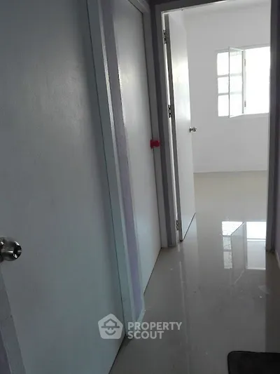 Bright hallway with glossy floors and open doors leading to sunlit rooms.