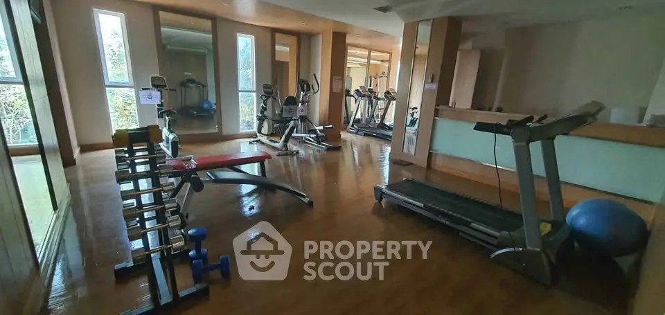 Spacious gym with modern equipment and wooden flooring in a residential building.