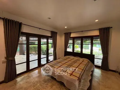 Spacious bedroom with large windows and garden view in a serene home setting.