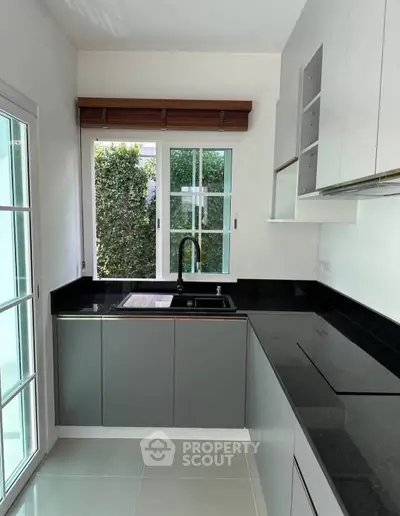 Modern kitchen with sleek cabinetry and large window for natural light.