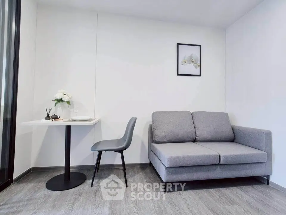 Modern minimalist living room with gray sofa and sleek dining area.