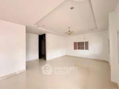 Spacious empty living room with modern ceiling design and chandelier, ready for customization.