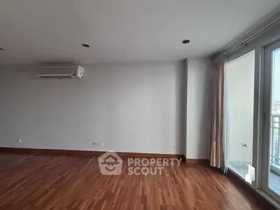 Spacious empty living room with wooden floors and balcony access