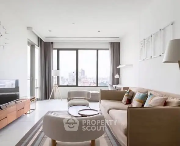 Spacious modern living room with large windows and stylish furniture in a high-rise apartment.