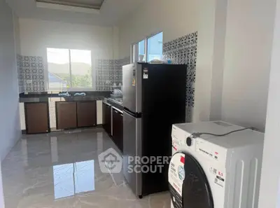 Modern kitchen with sleek appliances and stylish tile backsplash, featuring a washing machine and large refrigerator.