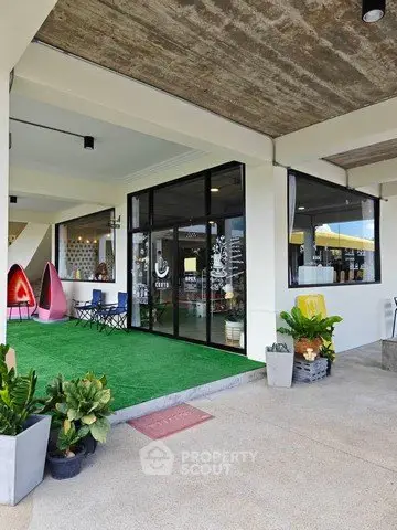 Modern commercial space with outdoor seating and artificial grass, ideal for a trendy cafe or retail shop.