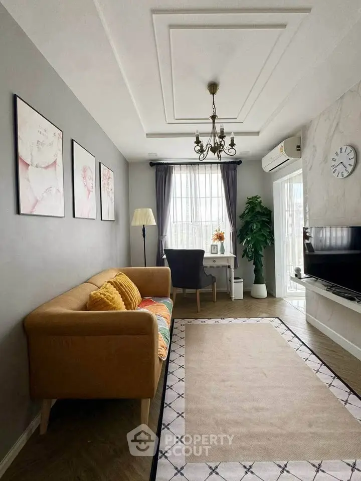 Charming living room with elegant decor, featuring a cozy sofa, stylish chandelier, and natural light from large windows.