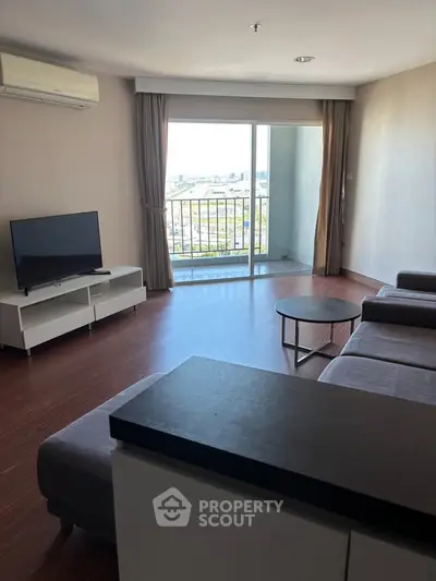 Spacious living room with modern furniture and balcony view in a high-rise apartment.
