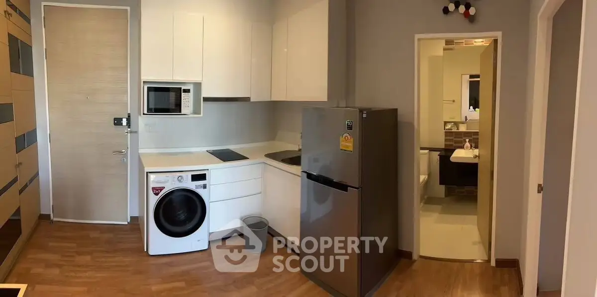 Modern kitchen with appliances and adjacent bathroom in a compact apartment layout.